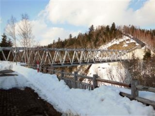 「ブルーリバー橋」(橋下に白髭の滝、右の山にシエルター)_十勝岳火山砂防情報センター