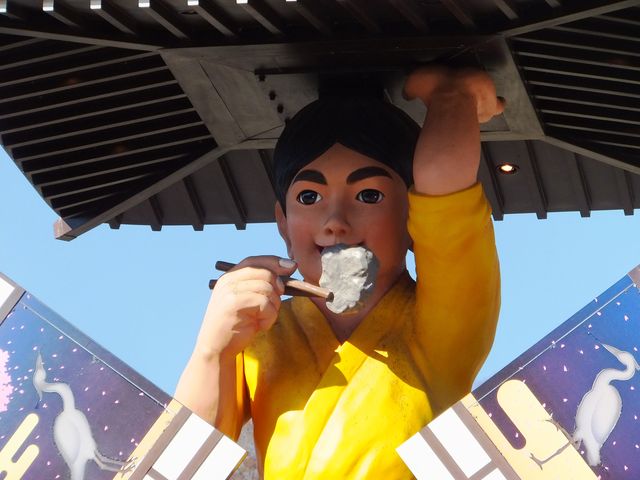 三歩太郎が箸でつまんでいるのはステーキやカツレツではありません。巨岩という想定です。_湯郷温泉からくり時計