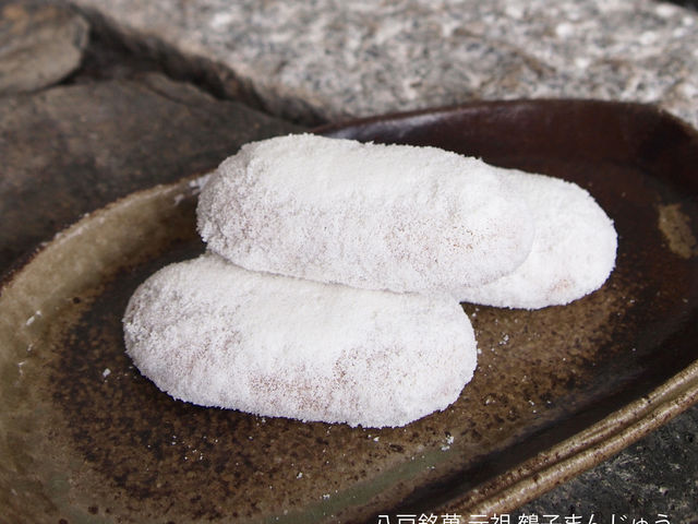 弊店発祥の八戸銘菓、元祖鶴子まんじゅう。黒糖を使用した生地に餡を包み焼き上げ、白い落雁粉をまぶした味わい深いお菓子です。_元祖鶴子まんじゅう萬榮堂