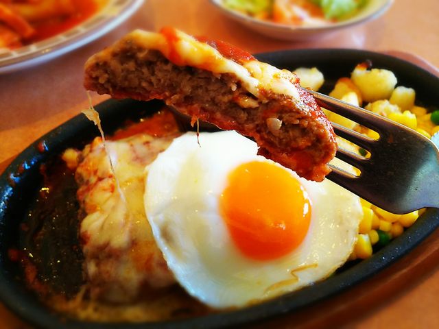 目玉焼きが嬉しいイタリアンハンバーグをフォークでパクリ!_サイゼリヤ 長野駅前店