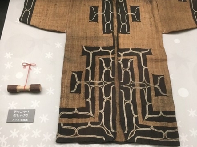 ルウンペ(テープ状の生地を縫い付けてその上から刺繍を施す)のアットゥシ(木の内皮を織った生地)_旭川市博物館