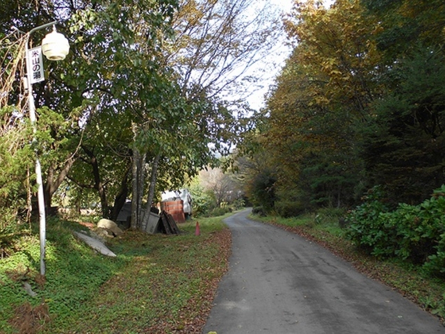 地図に掲載のない宿への専用道を進みます。右手に小山があり、小川が流れています。_米山の湯