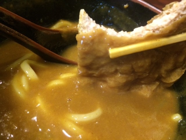 たっぷりカレーのルーがかかったおあげをガブリ_日の出うどん