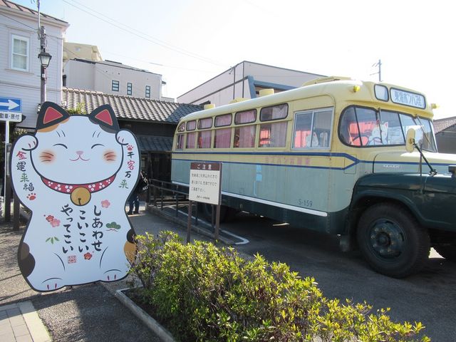 建物前の広場、バスの窓から猫(絵)が覗く_招き猫ミュージアム