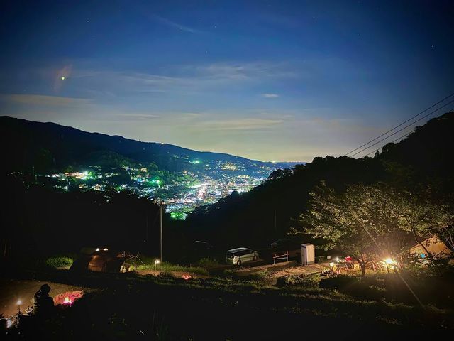 段々畑状のキャンプサイトに焚き火やライトの光が灯り、夜景をバックに写真映え抜群!_GROVE camping hill