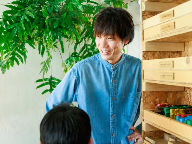 営業日はおもちゃ作家の金子周平がお客さんのそばで、遊び方を丁寧に伝えたり、世間話をしたりするなど、家族が楽しめるひとときになるような関わりを意識している。_ビー玉と木のおもちゃアトリエマーブル