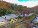 【秋の名月荘の全景】紅葉に染まる山のふもとに、静かに広がる名月荘の全景。