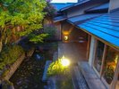 【灯りに包まれる、夕暮れの中庭】夕暮れの灯りに包まれ、中庭の水辺と木々が静かな表情を見せます。