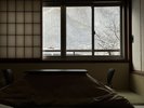 【客室:仙岳荘和室】雪景色を望む和室。障子越しの光とこたつが冬ならではの静かな寛ぎを演出します。