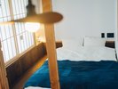 【スタンダードルーム 丸】ダブルベッドには藍染ファブリックのカバーをかけておもてなし