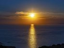 夕方、海にオレンジの道を作り、水平線の向こうに沈む夕日(西側の客室やエントランス前)