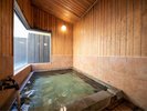【内湯】窓の大きく、光彩差し込む明るい室内の温泉。木のぬくもりを感じる空間でのんびりと。