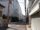 N路地を1〜2分直進、右手の焼肉千光苑を過ぎ50m程先このT字路を左へ。(T字路左奥の建物が当館です)