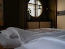 【和室12畳トイレ付】布団に寝転んで見上げる丸窓。窓の形に合わせた飾り棚に、かつての職人の粋を感じる