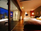 渚の館DX和洋室のベッド。ガラス張りの浴室越しに屋上庭園がみえます。