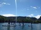 「志賀高原ビワ池・SUP体験」ボードの上に立ちパドルで漕いで水上を進むウォータースポーツ