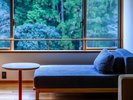 【緑翠スイート】窓際のソファで横になり、外に広がる自然の風景をゆったりとご堪能いただけます