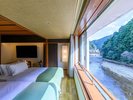 【山翠スイート】窓際のベッドから、目の前を流れる川のせせらぎと豊かな森の景色をお楽しみいただけます