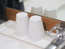 洗面台に整然と並ぶ、ホテルの白いコップ。清潔感と気配りが感じられる、さりげないおもてなし。