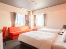【ツインルームB】オレンジのソファーが印象的な温かみのあるお部屋でございます。