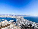 【函館山からの眺望】雪化粧した函館の街並みと青い海が広がる、冬ならではの美しい大パノラマ。