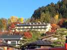 秋、中橋より望む城山の紅葉に囲まれる当館