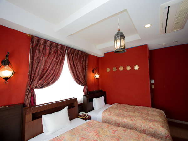 ◆部屋-ツインベッド-◆情熱的な赤色の壁の部屋。窓が大きく朝の光が優しく差し込む。