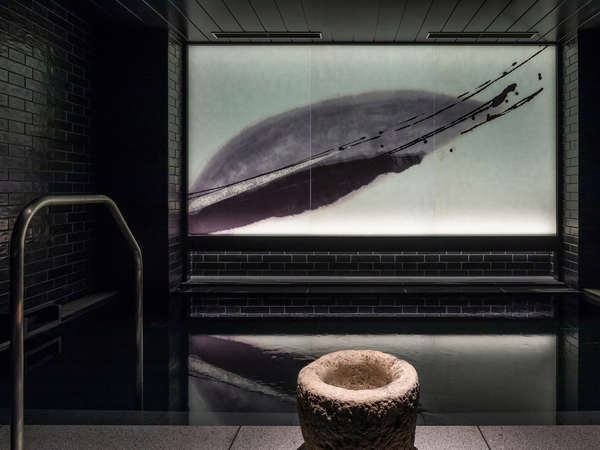 【男子大浴場】手水鉢と水墨画アートが幻想的に浮かび上がる。アートのコンセプトは「無常」