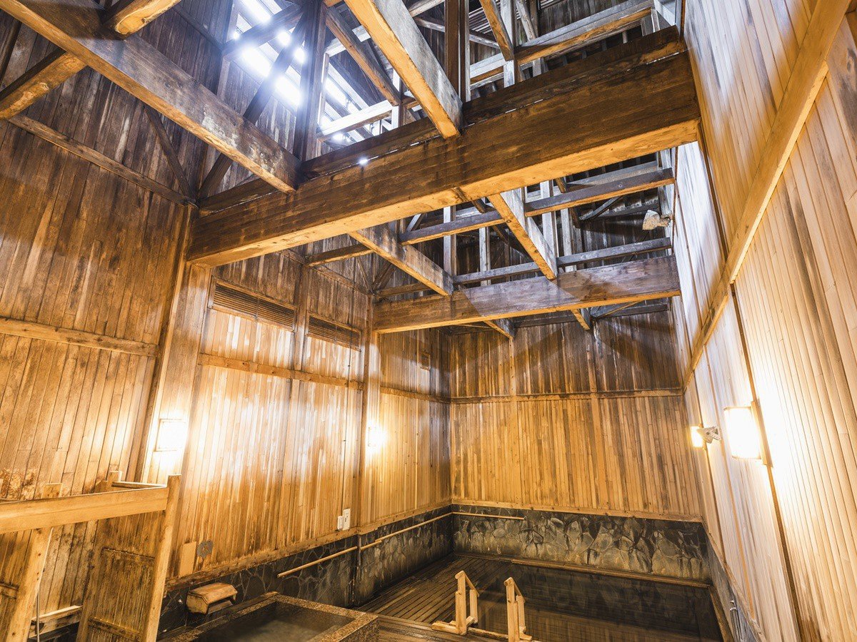【大浴場】「泉響の湯」浴槽から梁（はり）までの高さが最頂部で12メートルと開放的な空間。