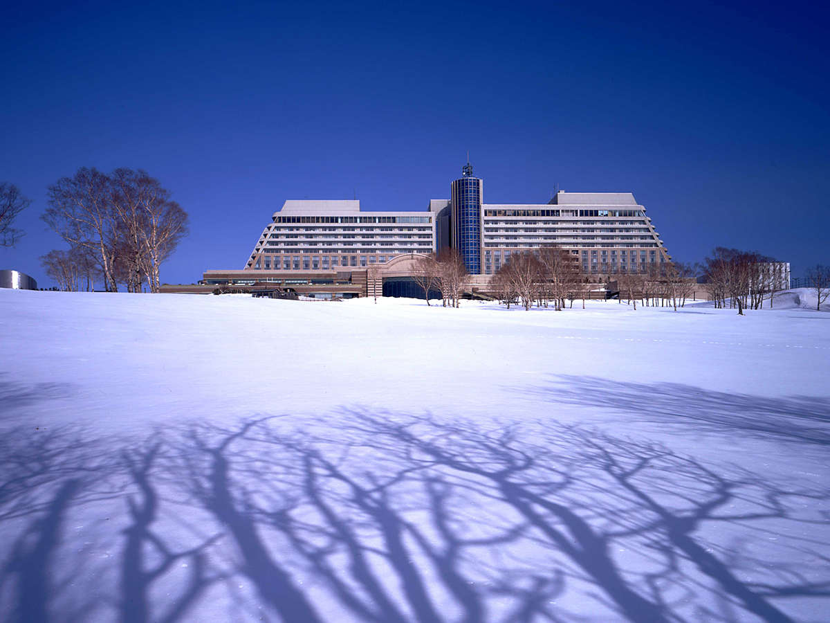 【外観】〔冬〕 銀世界に佇む、冬のウィンザーホテル。やわらかな雪が音を吸い込み、静けさに包まれます