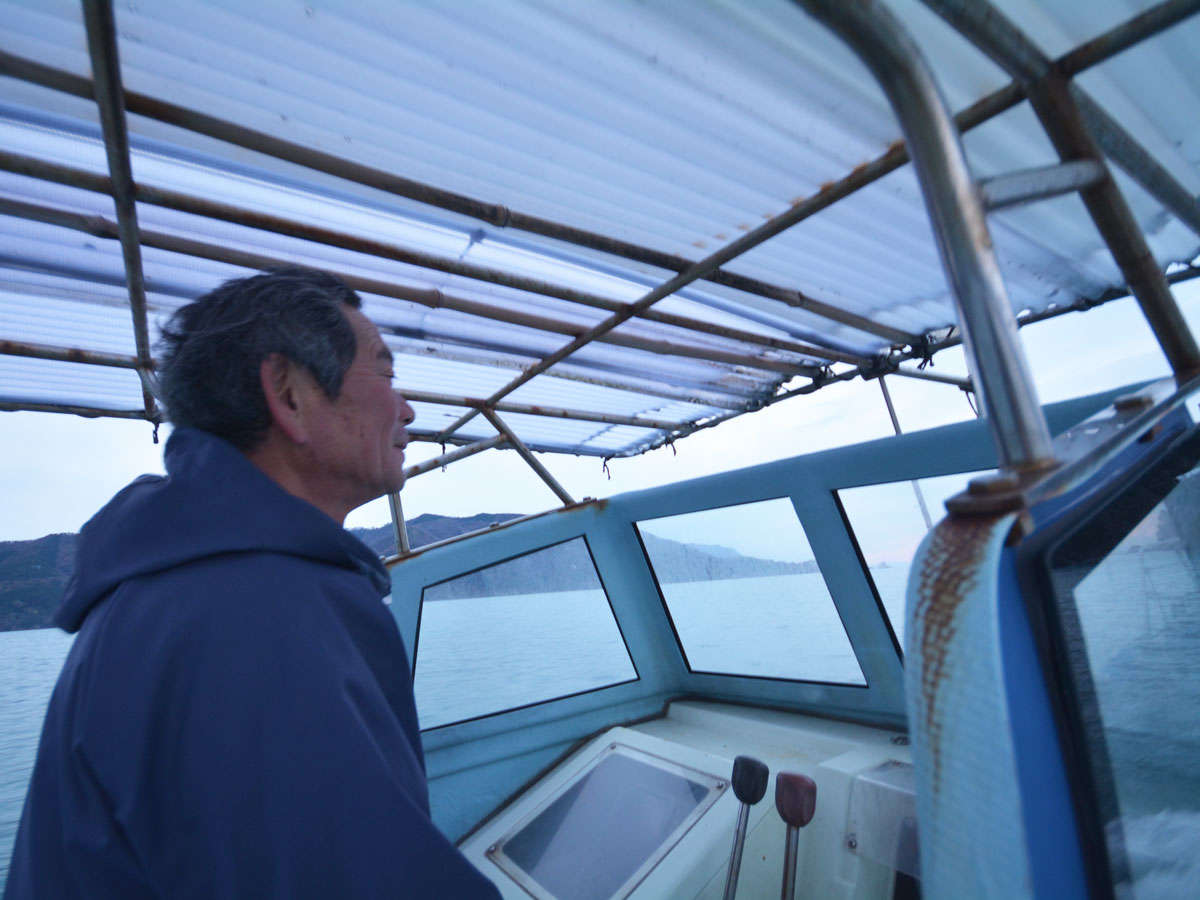 「まつみや丸」に乗る主人。現役漁師の宿です