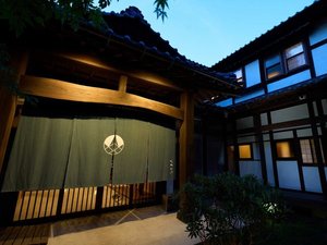 夕暮れの正面玄関風景。宿場町を思わせる雰囲気の空間です。藍色の暖簾が風格を醸し出しています。
