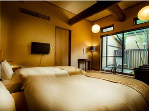 【新館・春花】春をイメージした洋室で、交差する梁は森のロッジのような趣。専用の坪庭とウッドデッキ付。