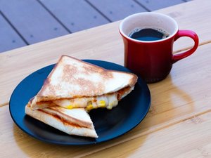 ご朝食のホットサンド。ピザソースの上にコーンやウィンナーが入ったピザ風のホットサンドです。