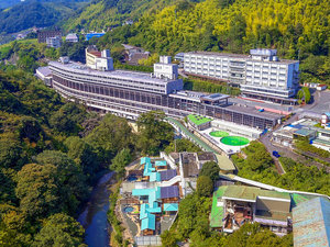 ドローンを使って上から。杉立山と石手川の渓谷沿いに佇む緑豊かなホテルです。