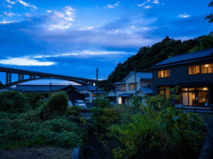 橋の向こうに夕空窓にはあたたかな灯り。小宿YAMADAYAで過ごす夜が始まる。