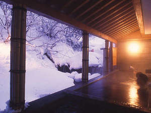 【冬】当館自慢の天然温泉露天風呂。川の流れと雪景色は格別です。