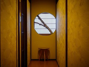 丸窓の光がやさしく揺れる、食事処へ続く和の廊下