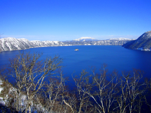 冬の摩周湖です。とても綺麗な青い湖の周りを、白く雪に覆われた山々が囲む絶景です。_摩周湖